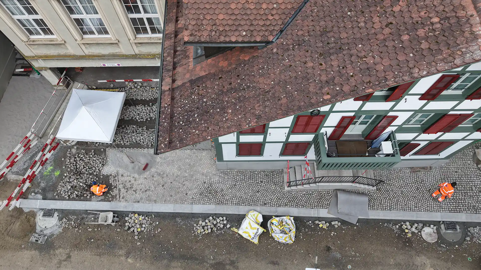 Luftbild der Baustelle Laupen mit Bauarbeiter, die Pflastersteine im Bogenmuster legen